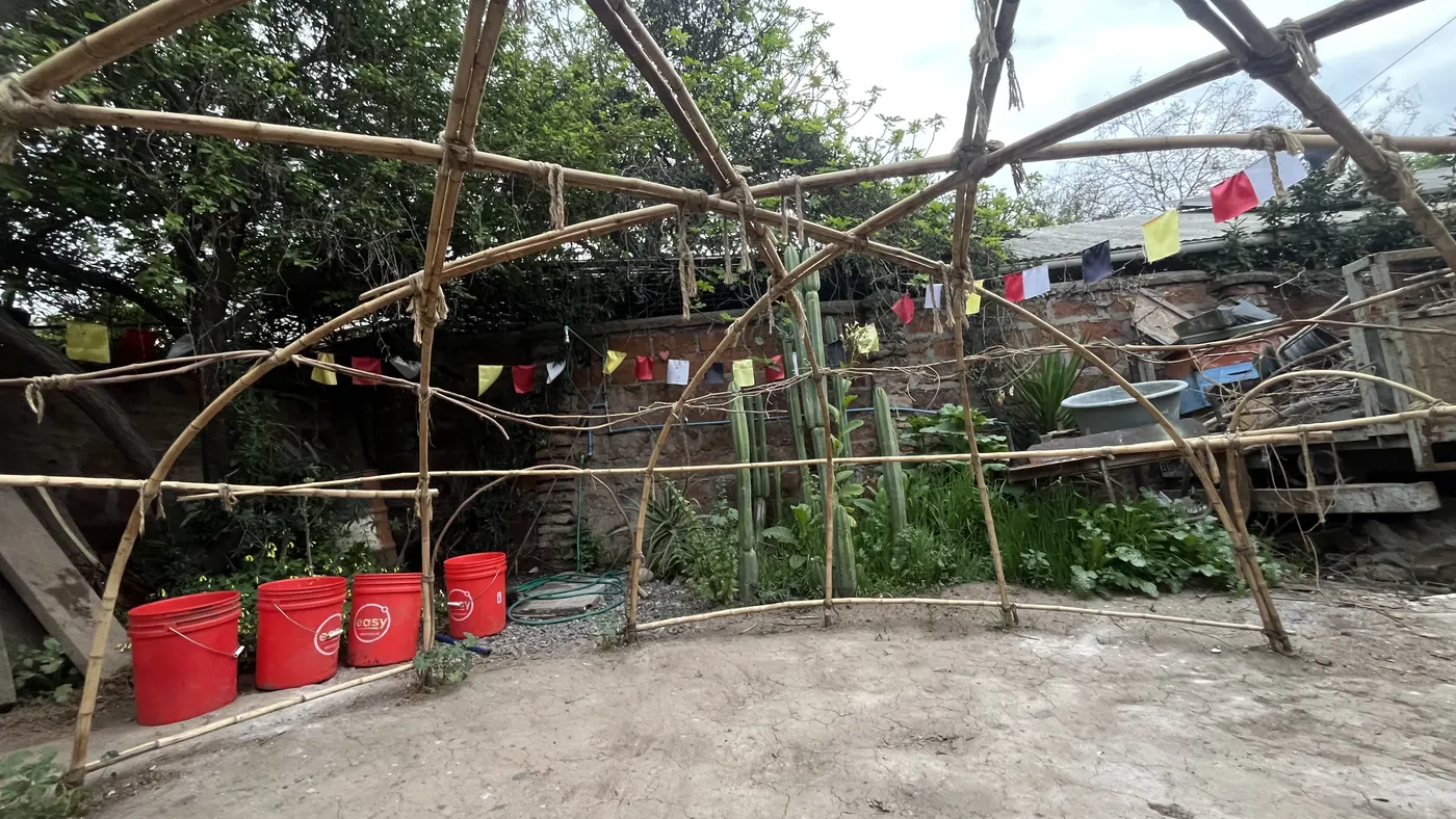 El domo del temazcal, hecho de varas amarradas, en el patio con cactus y banderitas de colores